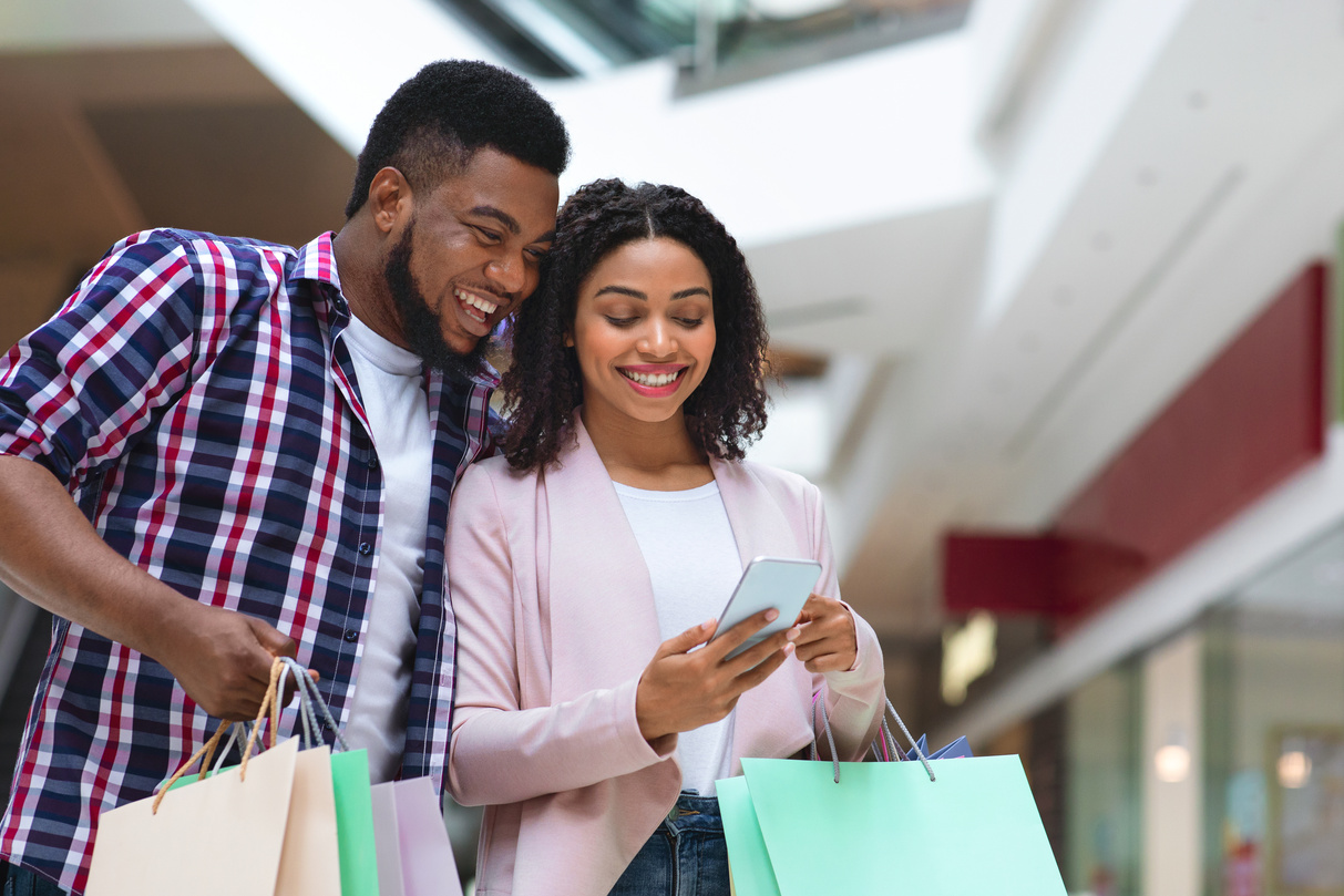 Cashback Concept. Happy Black Couple With Smartphone Checking Bank Account After Shopping